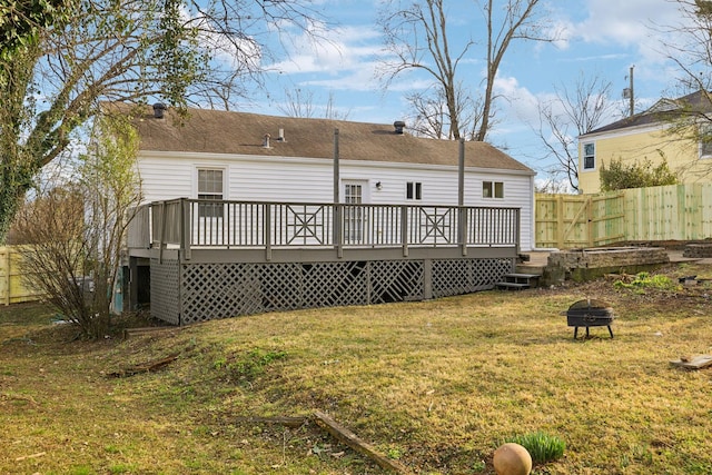 rear view of property with a yard, an outdoor fire pit, fence, and a wooden deck