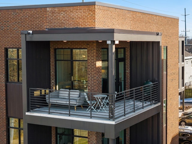 back of property featuring brick siding and a balcony