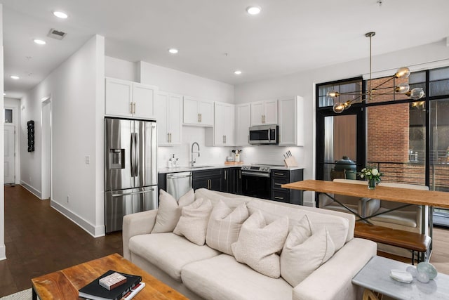 living room with baseboards, visible vents, dark wood-type flooring, and recessed lighting