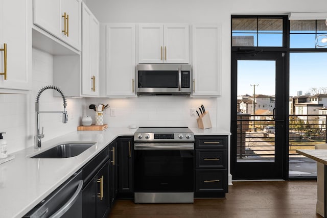 kitchen with appliances with stainless steel finishes, white cabinets, light countertops, and a sink