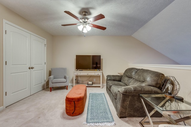 living area with carpet floors, vaulted ceiling, a textured ceiling, and a ceiling fan