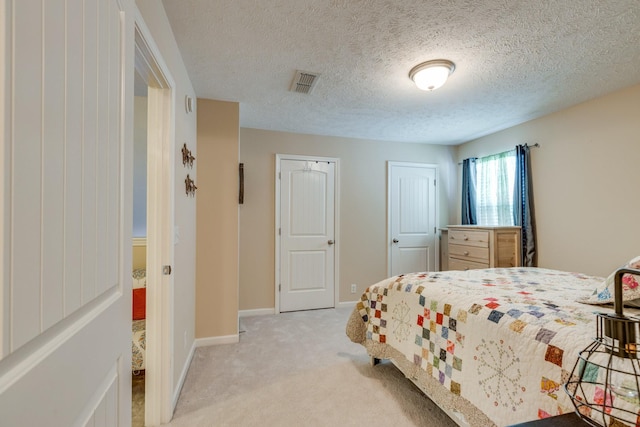 bedroom featuring a closet, light colored carpet, visible vents, a textured ceiling, and baseboards