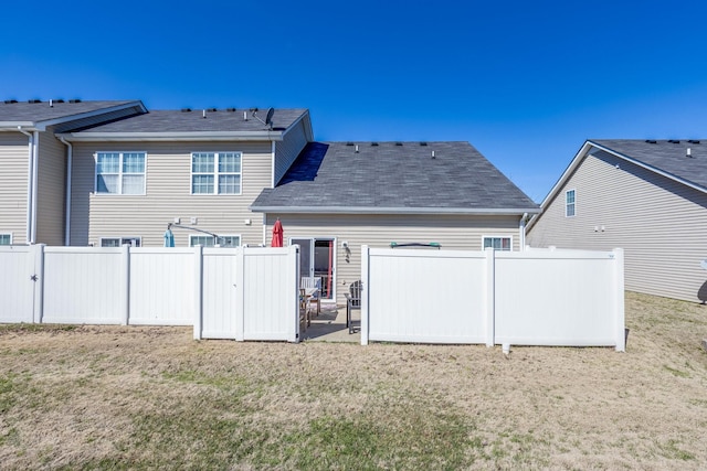 rear view of property featuring a yard, fence, and a patio