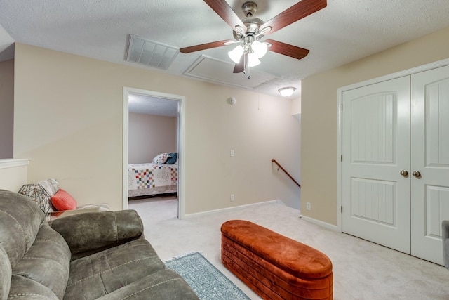 living room with attic access, visible vents, light carpet, and a textured ceiling