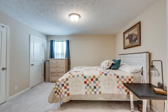 bedroom featuring light carpet, a textured ceiling, and baseboards