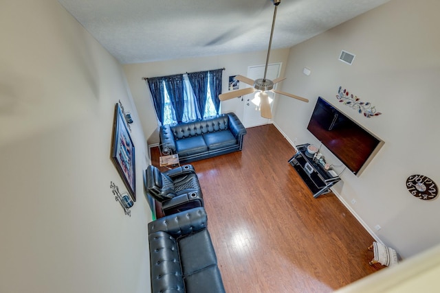 living room with wood finished floors, visible vents, baseboards, vaulted ceiling, and a ceiling fan