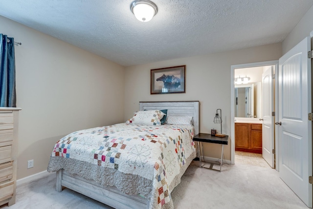 bedroom with light colored carpet, ensuite bath, a textured ceiling, and baseboards