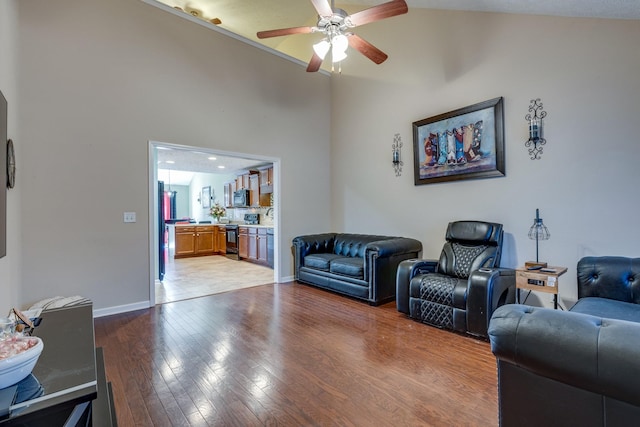 living area featuring high vaulted ceiling, baseboards, light wood finished floors, and a ceiling fan