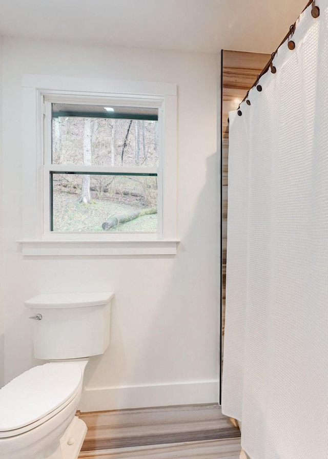 full bathroom with baseboards, toilet, and wood finished floors