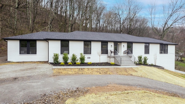 view of front facade featuring driveway, a shingled roof, crawl space, and brick siding