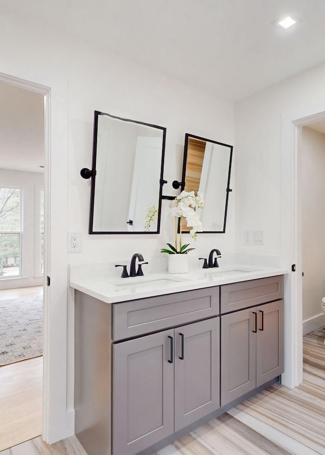 full bathroom with double vanity, a sink, and wood finished floors