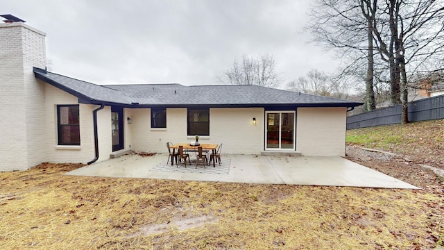 rear view of house featuring a chimney, fence, a patio, and brick siding