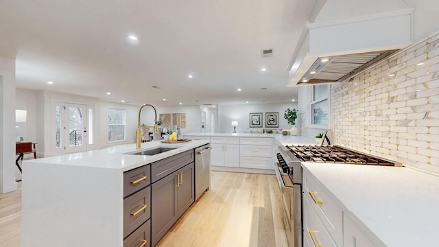 kitchen featuring light wood finished floors, white cabinets, appliances with stainless steel finishes, a sink, and recessed lighting