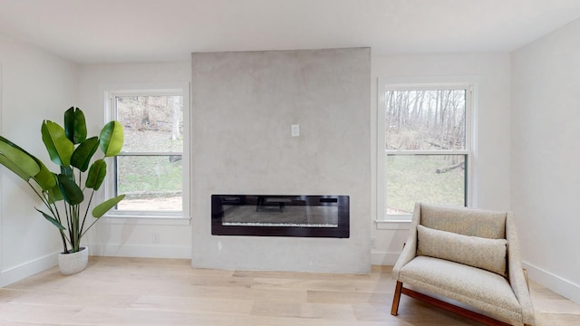 sitting room with baseboards, wood finished floors, and a glass covered fireplace