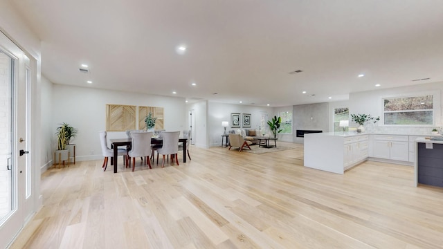 dining room featuring light wood-type flooring, a fireplace, baseboards, and recessed lighting