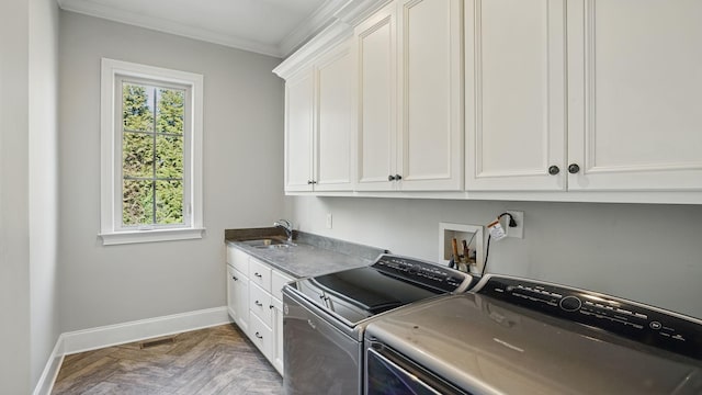 clothes washing area featuring cabinet space, ornamental molding, washing machine and dryer, a sink, and baseboards