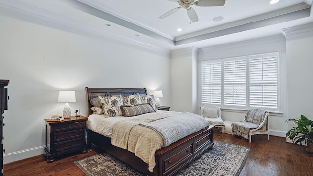 bedroom with a raised ceiling, crown molding, baseboards, and wood finished floors