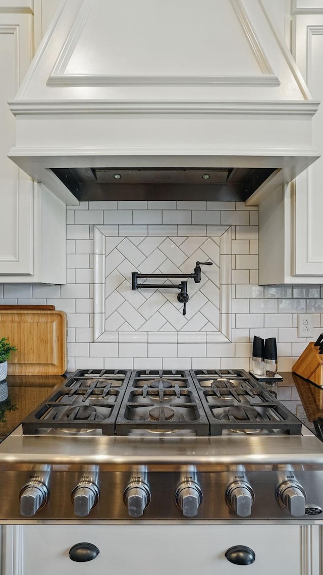 kitchen with white cabinetry, stainless steel gas stovetop, and backsplash