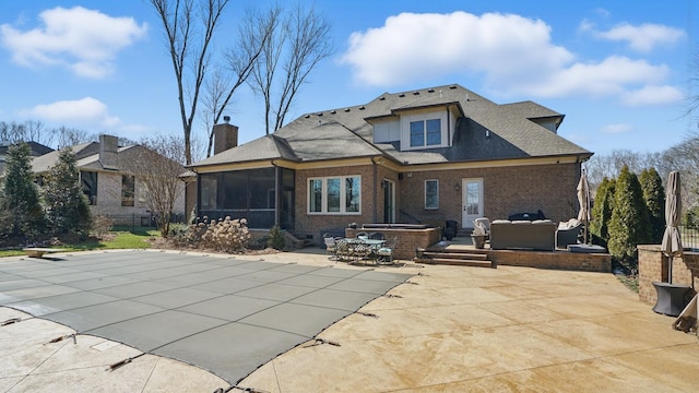 back of house featuring brick siding, a patio, a chimney, an outdoor hangout area, and a sunroom