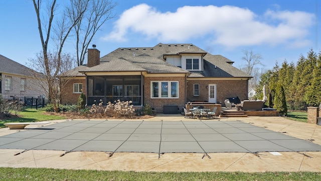 rear view of house with a sunroom, a chimney, fence, a patio area, and brick siding