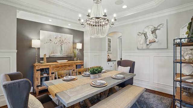 dining room featuring arched walkways, a notable chandelier, a decorative wall, and a tray ceiling