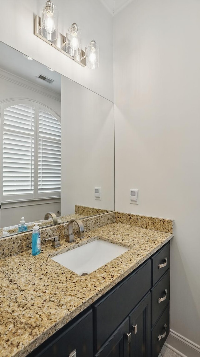 bathroom featuring baseboards, visible vents, ornamental molding, and vanity