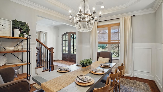 dining area featuring arched walkways, a raised ceiling, stairs, french doors, and a chandelier