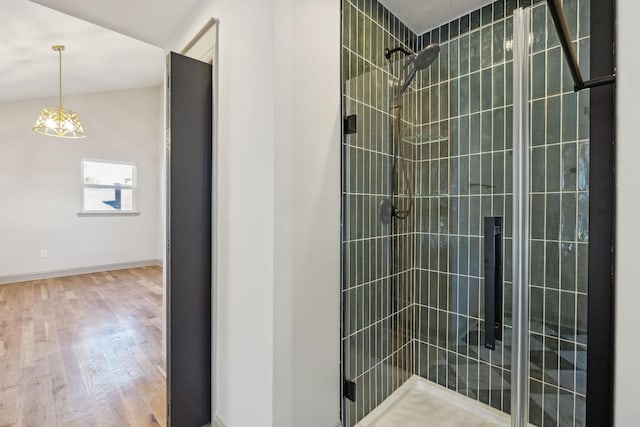 bathroom featuring lofted ceiling, wood finished floors, a shower stall, and baseboards