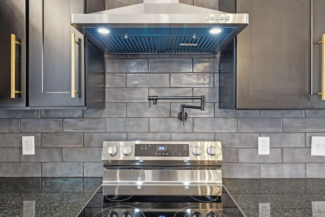 kitchen with dark stone counters, electric range, wall chimney range hood, and tasteful backsplash