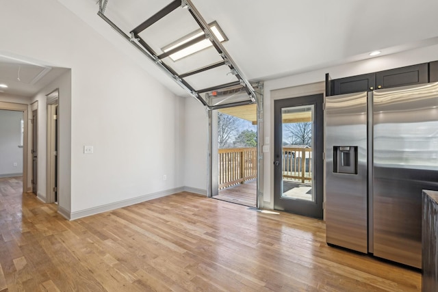 interior space with light wood-style flooring, baseboards, and stainless steel refrigerator with ice dispenser