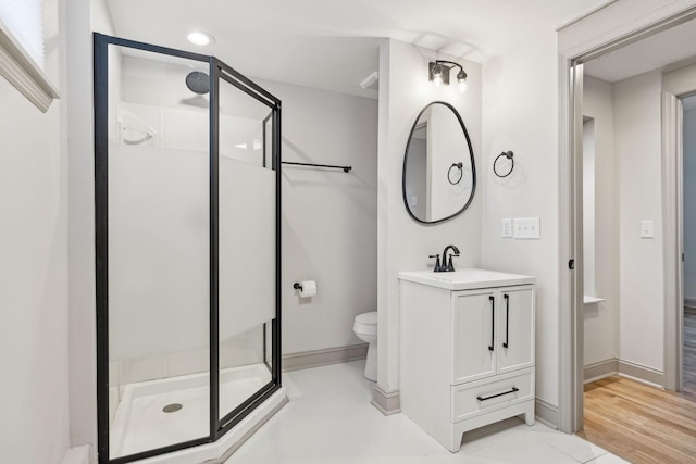 bathroom featuring baseboards, a shower stall, toilet, and vanity