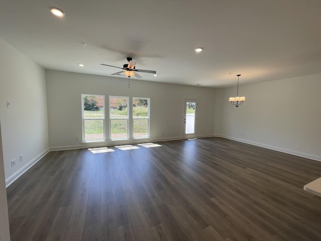 unfurnished living room with ceiling fan with notable chandelier, baseboards, dark wood-type flooring, and recessed lighting