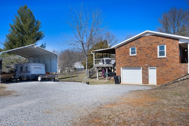 view of side of property featuring a garage, brick siding, stairway, gravel driveway, and a detached carport