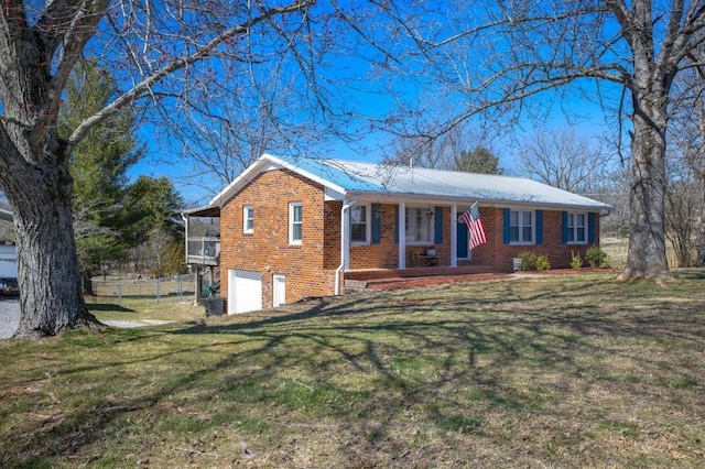 ranch-style home featuring metal roof, an attached garage, brick siding, fence, and a front lawn