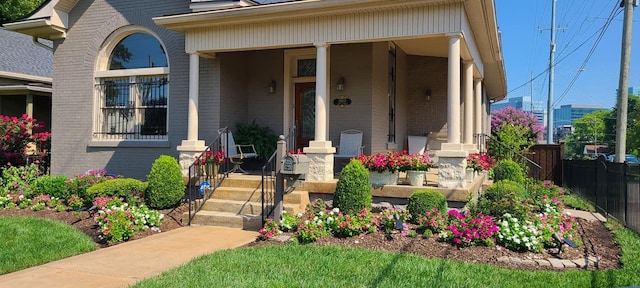 view of front of property with covered porch, fence, and brick siding