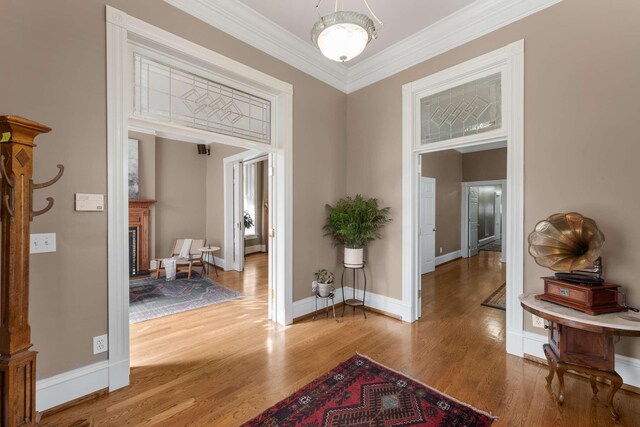 hall featuring baseboards, ornamental molding, and wood finished floors