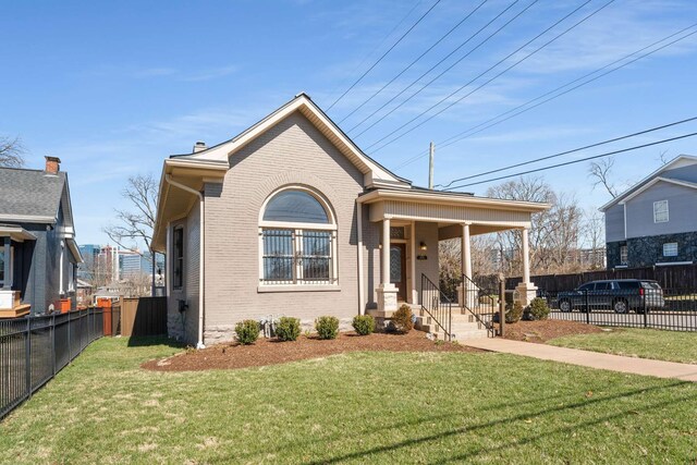 view of front of home featuring brick siding, fence, a chimney, and a front lawn