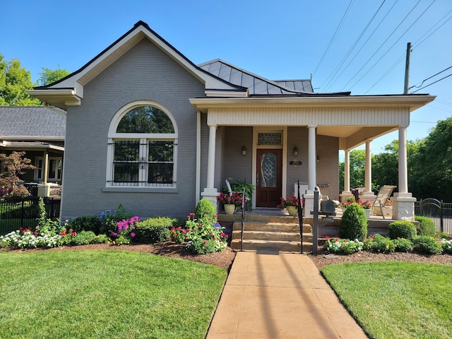 view of front of home featuring brick siding, a standing seam roof, and a porch