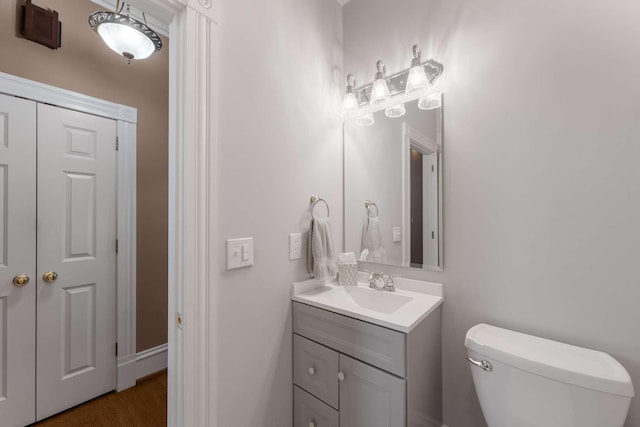 bathroom with toilet, wood finished floors, and vanity