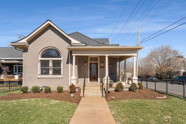 view of front of property with a standing seam roof, brick siding, fence, and covered porch