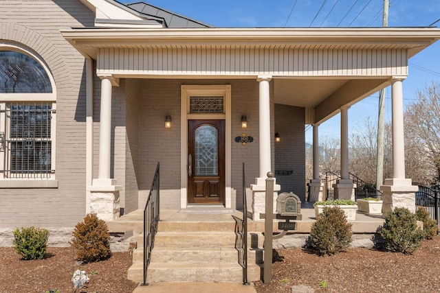 entrance to property with covered porch and brick siding