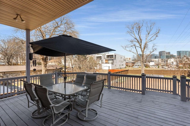 wooden deck with a view of city, fence, and outdoor dining area