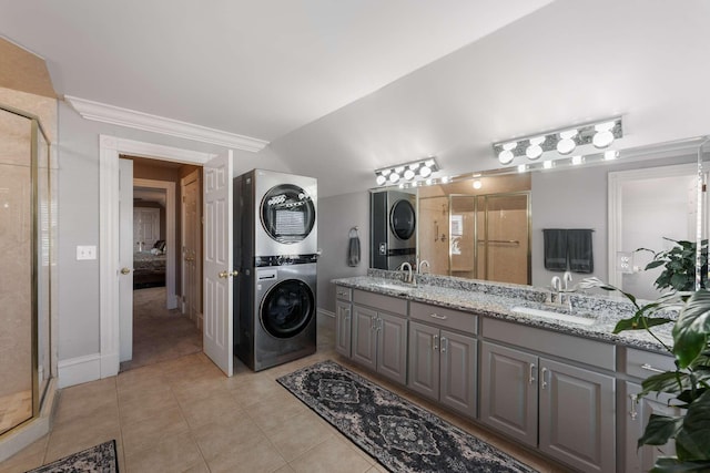 ensuite bathroom with stacked washing maching and dryer, a sink, tile patterned flooring, and a shower stall