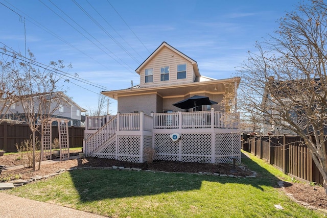 rear view of house with a fenced backyard, a wooden deck, and a yard