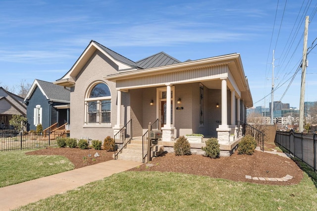 view of front facade featuring brick siding, a porch, a standing seam roof, fence, and metal roof