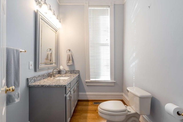 bathroom with visible vents, baseboards, toilet, wood finished floors, and vanity