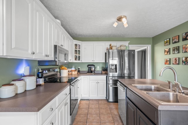 kitchen featuring appliances with stainless steel finishes, a sink, glass insert cabinets, and white cabinets