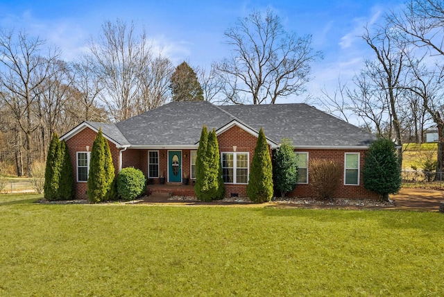 ranch-style house with crawl space, roof with shingles, a front lawn, and brick siding