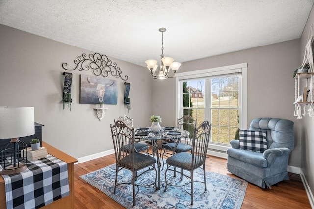 dining room featuring baseboards, a textured ceiling, an inviting chandelier, and wood finished floors