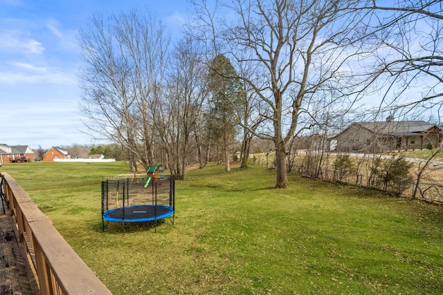 view of yard featuring a trampoline and fence